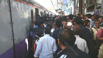 People walking out of a train at a crowded train station in Mumbai.