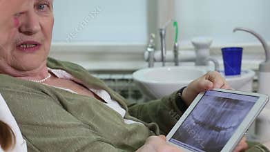 Close up of dentist and elderly patient talking while looking at X- ray