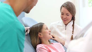 Close up of girl in dental chair shows with finger aching tooth