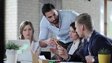 Four young multicultural start uppers discuss plan of business in the light modern office.