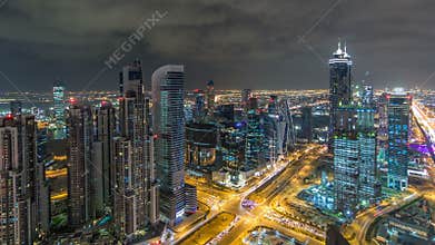 Dubai business bay towers illuminated at night timelapse. Rooftop view of some skyscrapers and new towers under