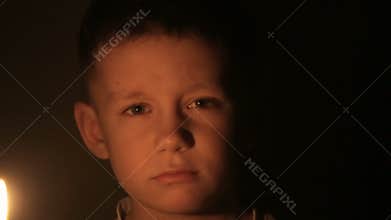 A child holds a burning candle in his hands