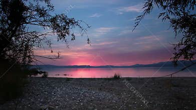 Sea of galilee through trees at sunset