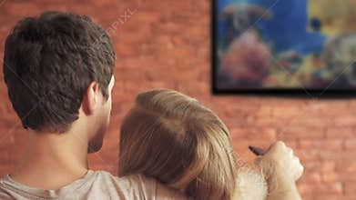 Smart tv and couple pressing remote control.