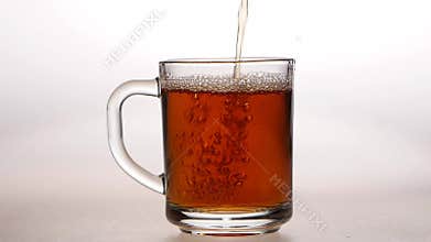 Glass cup is poured hot black tea. Slow motion, closeups