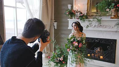 Photographer shooting bride with a bouquet and a fireplace on the background