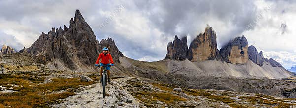 View of cyclist riding mountain bike on trail in Dolomites,Tre C