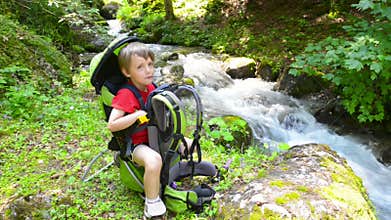 Boy relaxing in a kid carrier near river