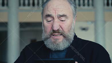 Sad old man chatting on the tablet in 4K