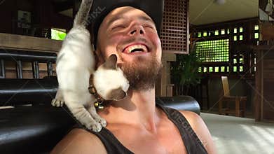 Cute Kitty Sitting on Young Man Shoulder and Rubs About His Beard. HD slow motion cat shot.