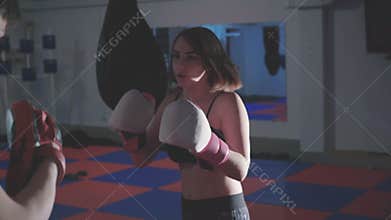 Pretty girl with trainer exercising kickboxing in gym in 4K