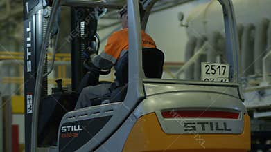 Worker Drives Forklift Truck to Wooden Pallets