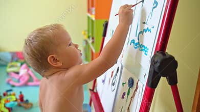 Cute boy painting on an easel