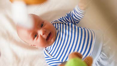 Newborn baby boy look at carousel toy spin over bed