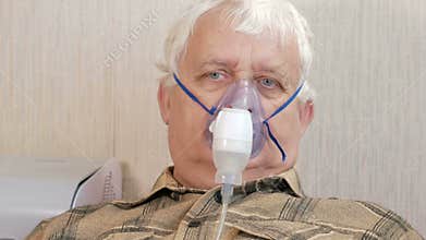An elderly man holding a mask from an inhaler at home. Treats inflammation of the airways via nebulizer. Preventing