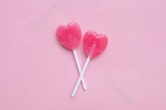Two Pink Valentine`s day heart shape lollipop candy on empty pastel pink paper background. Love Concept. top view.
