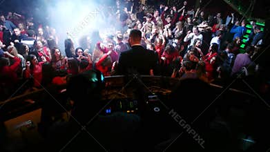 Crazy liberated dance party under the control of two DJs Exciting crowd floodlit