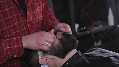 Closeup professional grooming beard with scissors in a Barbershop. Hipster concept. Portrait of a bearded man hipster in