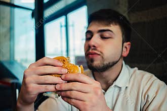 A young man with a beard looking at going to a burger and eat it
