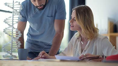 Young man joining his colleague while both studying genetics