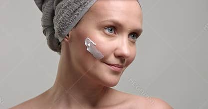 30s woman puts a cream on cheek