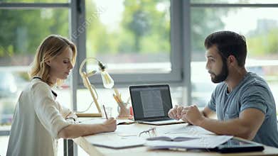 Serious millennial guy helping female groupmate with home assignment