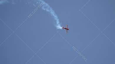 Red Su-31 aircraft shows the aerobatics figure Barrel roll in the middle of the blue sky