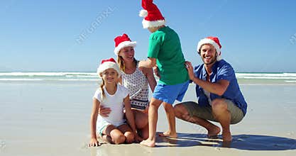 Happy family in santa hats posing at beach