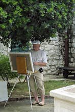 The artist stands in front of a canvas and paint