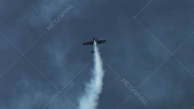 Plane doing aerobatics in blue sky with smoke tailing