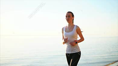 Young pretty sport woman running near the sea.