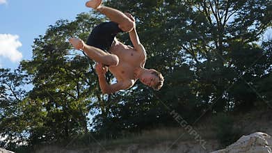 Man jumping sideflip on the beach at sunset. Freerunner jumping acrobatic stunt