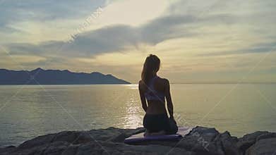 Drone view from girl sittings in yoga pose to ocean
