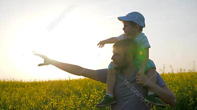 Relationships of child with daddy, dad with little boy go by field and point hand into distance, field walk of dad and