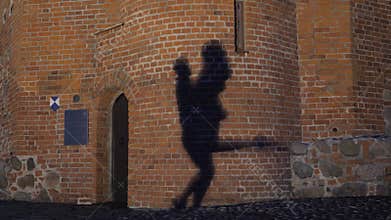 Silhouette of a couple in the shadow actively dancing on a stone wall.