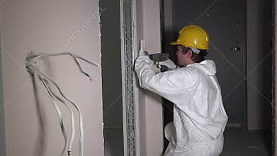 Builder worker light switch with electric drill tool in corridor