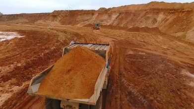Mining truck transporting sand at sand quarry. Aerial view of mining machinery