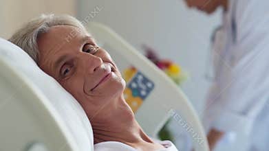 Cheerful retired man lying in a hospital bed