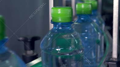 Water bottles with green caps on a conveyor. 4K.
