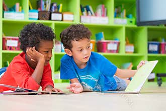 Two boy kid lay down on floor and reading tale book in preschoo