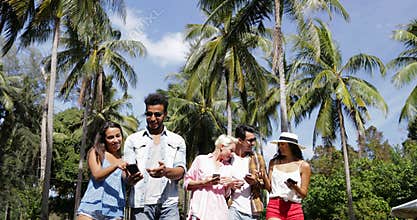 People Group Talking Use Cell Smart Phones Walking Outdoors Under Palm Trees, Happy Smiling Mix Race Man And Woman