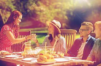 Happy friends having dinner at summer garden party