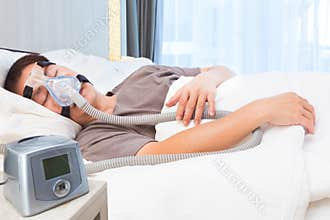 Middle age asian man sleeping wearing CPAP mask connecting to ai