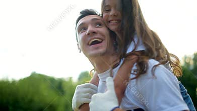 Beaming male volunteer holding charming girl on his back