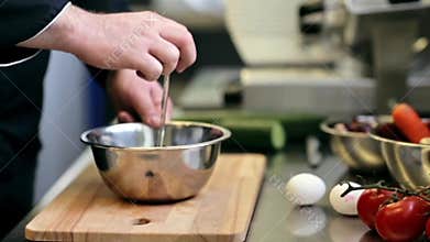 Hands of male chef cook breaking egg in kitchen