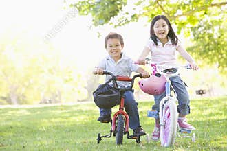 Brother and sister outdoors on bicycles smiling