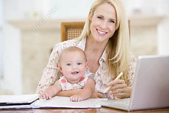 Mother and baby in dining room with laptop