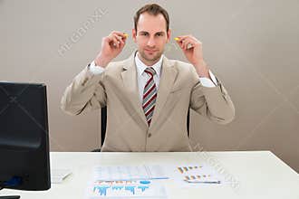 Businessman inserting earplug in ears