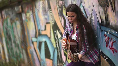 The girl with the guitar against a wall with