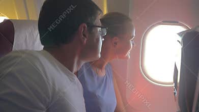 Woman and man looking out plane window